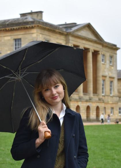 Photo of author Katie Kennedy standing in front of a historical building under an umbrella